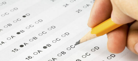 Hand completing a multiple choice exam.